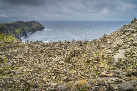 Many stone piles, rock balancing or stone stacking, in iconic Cliffs of Moher, popular tourist attraction, Wild Atlantic Way, County Clare, Ireland