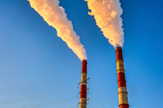 white smoke is coming out of the pipes in the blue sky. High quality photo