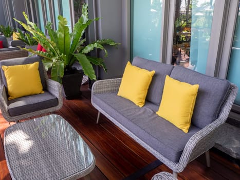 Interior photography of rattan outdoor furniture in a courtyard with garden beds and sandstone walls in the background
