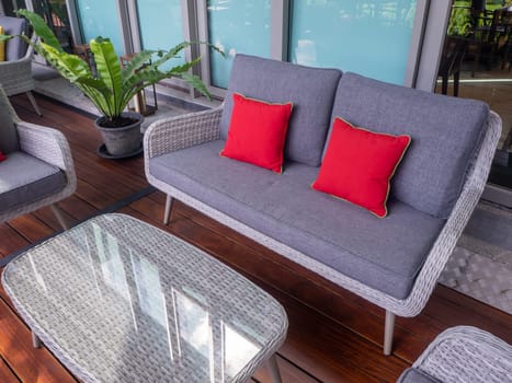 Interior photography of rattan outdoor furniture in a courtyard with garden beds and sandstone walls in the background