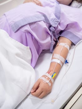 close up of saline solution on hand of women patient in pink clothes lying on the hospital bed