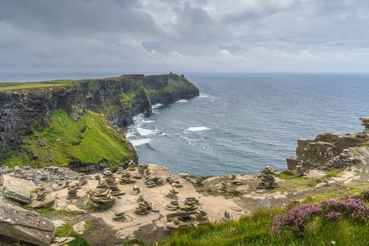 Stone piles, rock balancing or stone stacking on the edge of iconic Cliffs of Moher, popular tourist attraction, Wild Atlantic Way, Co. Clare, Ireland
