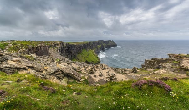 Panorama with rock balancing or stone stacking on the edge of iconic Cliffs of Moher, popular tourist attraction, Wild Atlantic Way, Clare, Ireland