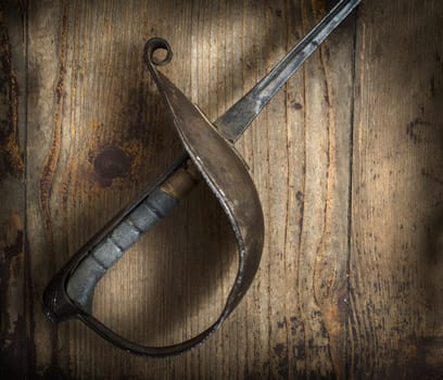 Old fencing sword on wooden background