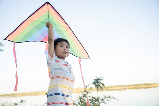 Asian happy children boy with a kite running to fly on in park at summer sunset outdoors