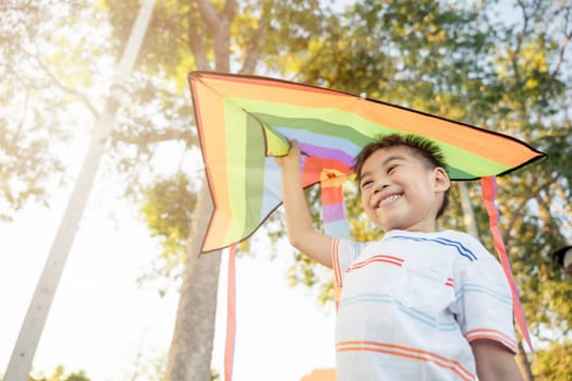 Asian happy children boy with a kite running to fly on in park at summer sunset outdoors