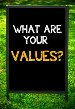 WHAT ARE YOUR VALUES?  message on sidewalk blackboard sign against green grass background. Copy Space available. Concept image