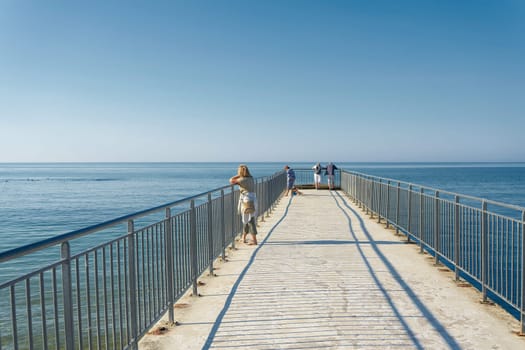 Holidaymakers on the small pier (Male Molo) on the beach of Kolobrzeg on the Polish coast of the Baltic Sea