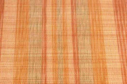 Colorful multi-colored abstract textile place mat with rows of color variation. Multiple warm and inspirational colors of orange, green and red in rows of this weaved textile place mat close-up..
