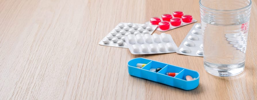 Different medicine pills and a glass of water with copy space