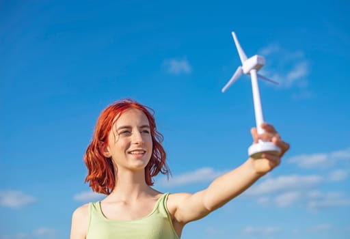 girl with wind turbine against blue sky