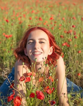 happy young girl with red hairs in poppy field