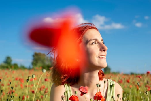 happy young girl with red hairs in poppy field