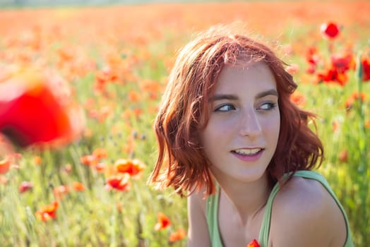 happy young girl with red hairs in poppy field