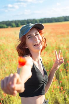 happy young girl with poppy flower showing victory sign