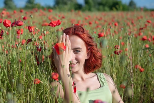 happy young girl with red hairs in poppy field