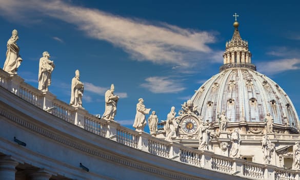 Statues of Catholic Saints. Decorations on Bernini colonnade, Saint Peter Cathedral, with the Cupola in background - Rome, Italy