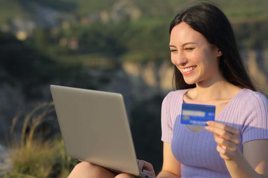 Asian woman buying online with credit card and laptop in the mountain