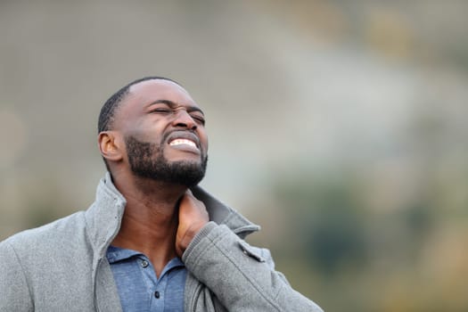 Man with black skin suffering neck ache outdoors in winter