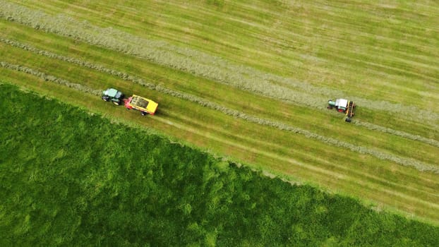 Aerial shot with drone of two tractors harvesting hay in a meadow in Bavaria