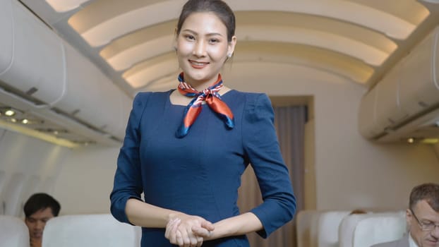 Beautiful flight attendant standing waiting for the passengers to board inside the plane in the airport, air hostess smiling in uniform looking at camera in private airplane