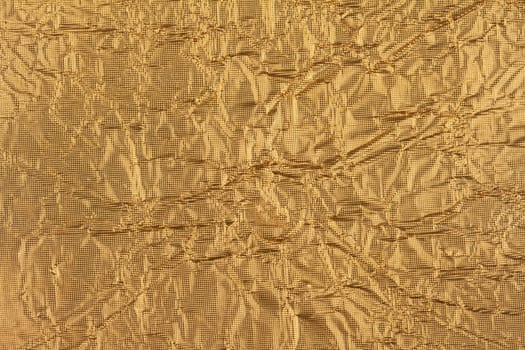 top view detail closeup of textured wrapping paper gold foil leaf with wrinkled surface and embossed decoration