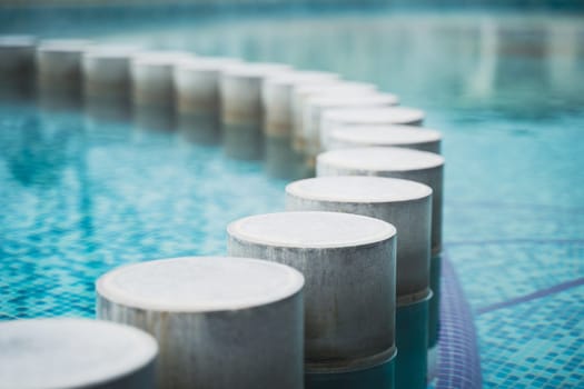closeup perspective view of pool with blue water and row of decorative concrete pillars