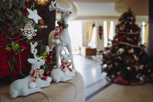 closeup front view of Christmas festive decoration with white plush textile reindeers wearing warm red scarfs and globes