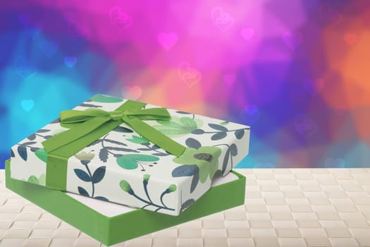 Happy Valentine or Mothers Day card template. 3D illustration of a beautiful colorful present box on table over abstract light pink blue pastel background with hearts. Space for text design.