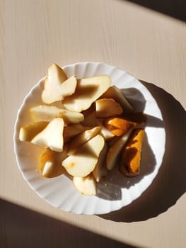 Sliced ​​pears on a white plate. Top to bottom view. Illuminated by a sharp light.