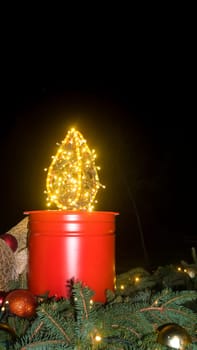 A large Advent candle made from a bucket. Christmas decoration on black background. Christmas atmosphere. An atmosphere of love, hope, peace, joy.