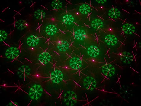 A beautiful shot of laser lights with star and firework shapes on the wall.