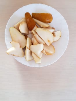 Sliced ​​pears on a white plate. Top to bottom view. Illuminated by a sharp light.