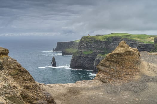 Sea stack and rock formations on iconic Cliffs of Moher, OBriens Tower in a distance, popular tourist attraction, UNESCO, Wild Atlantic Way, Ireland