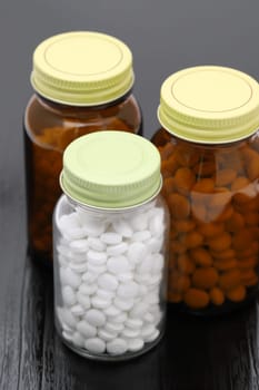 medical pills and glass bottle on black wooden table, medical for health