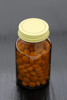 medical pills and glass bottle on black wooden table, medical for health