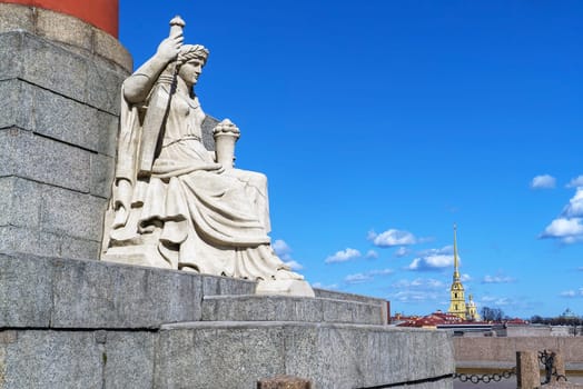 Sculpture on the Rostral column against the background of the Peter and Paul Cathedral. Saint-Petersburg.