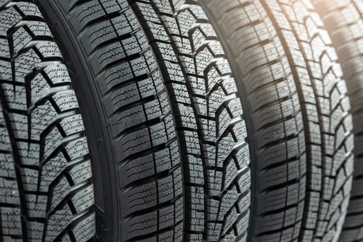 Detail of new winter tires for car with deep rubber patter to increase adhesion. Set of unused vehicle wheels for use in snow and on ice. Concept of safety on roads.
