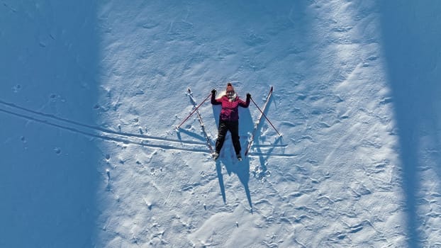Aerial shot with a drone of a woman with cross-country skis in the snow. Winter sports for seniors