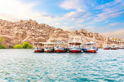 Traditional colorful egyptian boats in the Nile, Aswan hills, Egypt.