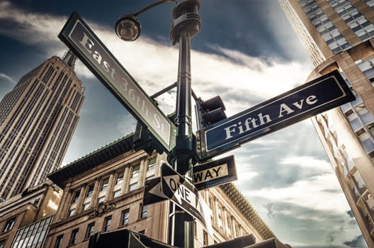 Fifth Ave 5th Ave, New York City sign, view from low angle with sunset and empire state building in thebackground, america, usa