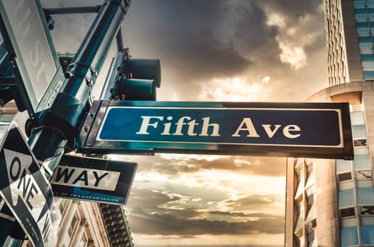 Fifth Ave 5th Ave, New York City sign, view from low angle with sunset and building in thebackground during a cloudy day, america, usa