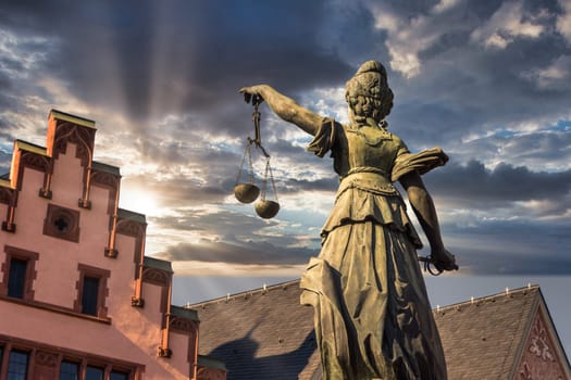 Justitia Monument view from back during dawn with sunset and clouds in background, frankfurt germany