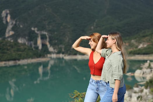 Two friends looking protecting from sun in the mountain on summer vacation