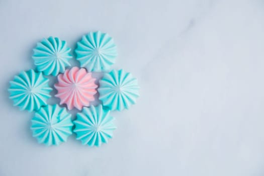 A flower with turquoise petals and a pink core made of meringue lies on a light marble background with a place for text. High quality photo