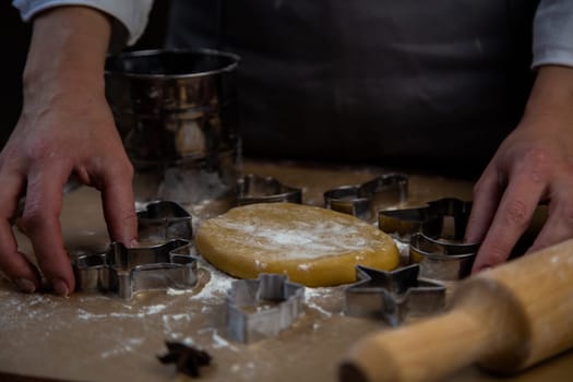 The rolled dough in the form of a circle lies on baking parchment surrounded by cookie cutters. High quality photo