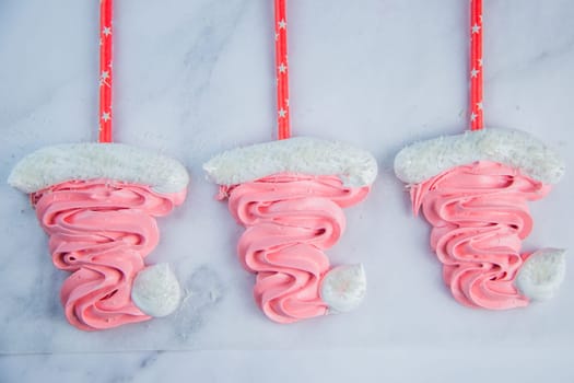 Santa Claus Christmas hats made of pink bizet on red sticks are lying on baking paper. High quality photo