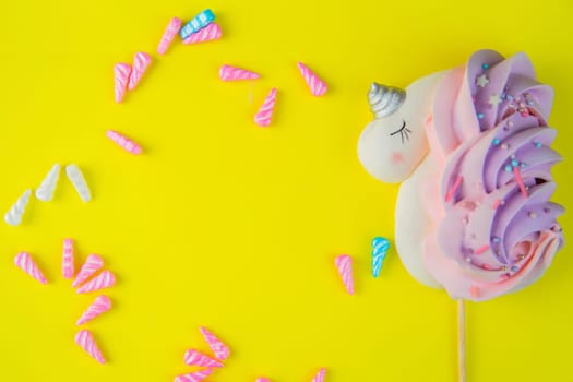 A bizet unicorn is white with a pink-purple tail and a silver horn lying on the side of a bright yellow background, multicolored horns are scattered around the circle, there is a place for text in the middle. High quality photo