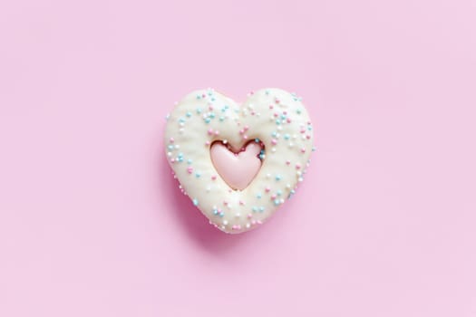 Flat lay of heart shaped gingerbread cookie with sprinkles and icing on pink background. Top view of tasty Valentine's Day bakery, homemade bakery for romantic holiday