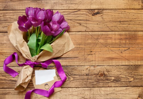 Purple tulips Bouquet and blank card on wooden table top view
